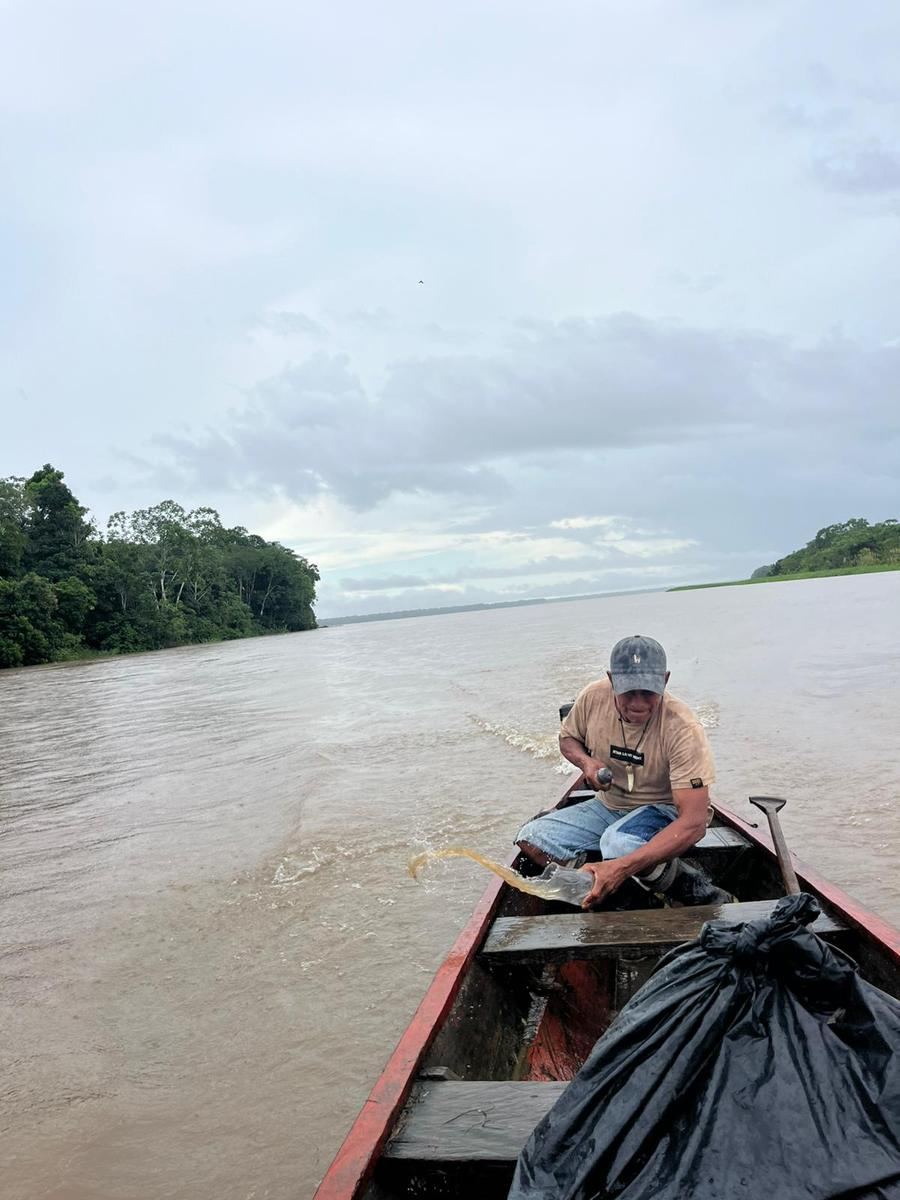 Une pirogue à moteur sur le fleuve large, sous un ciel bas et couvert