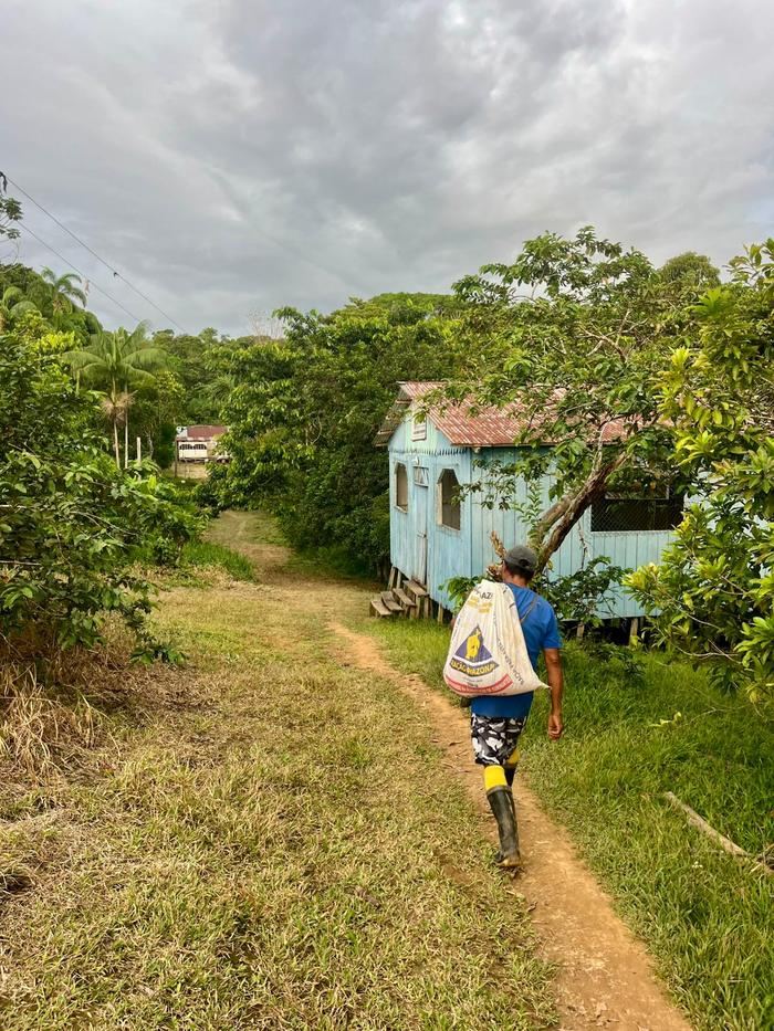 Un habitant marche sur le chemin du village, un sac sur l'épaule