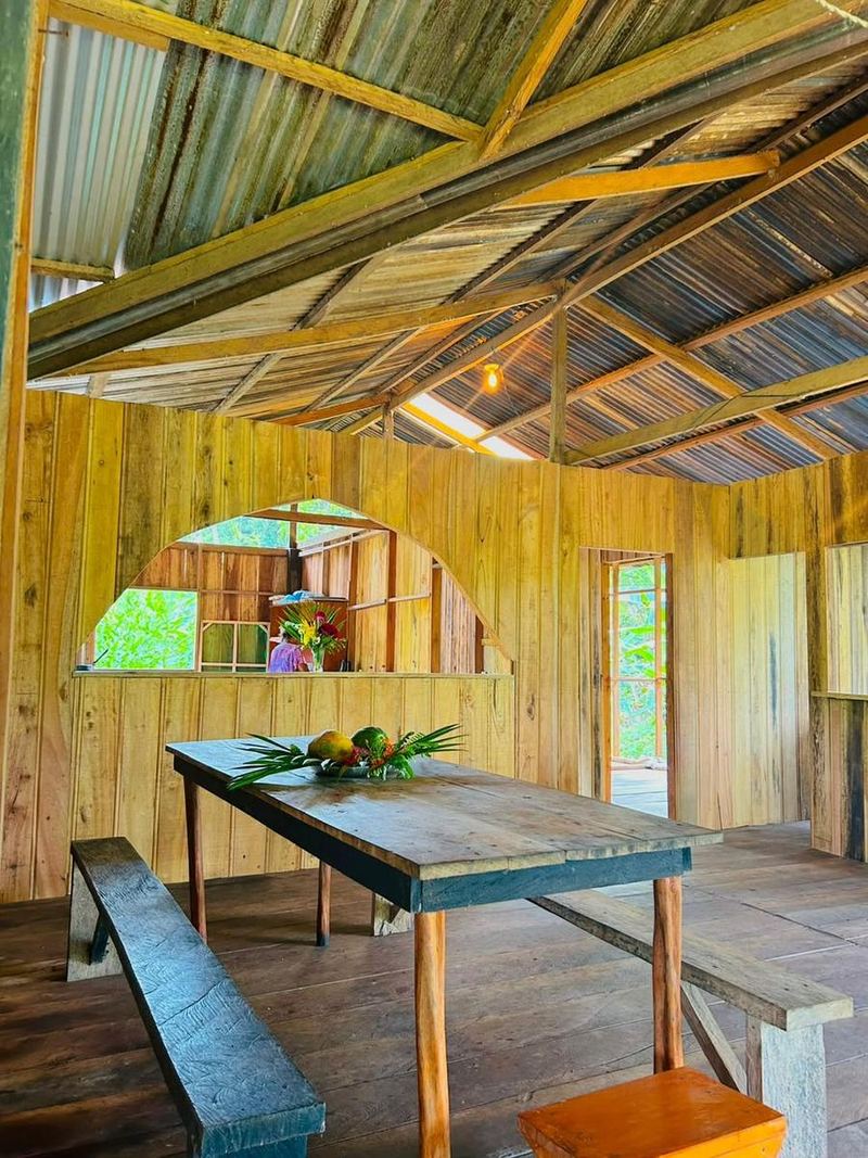 Le réfectoire, grande table de bois et bancs sous la charpente