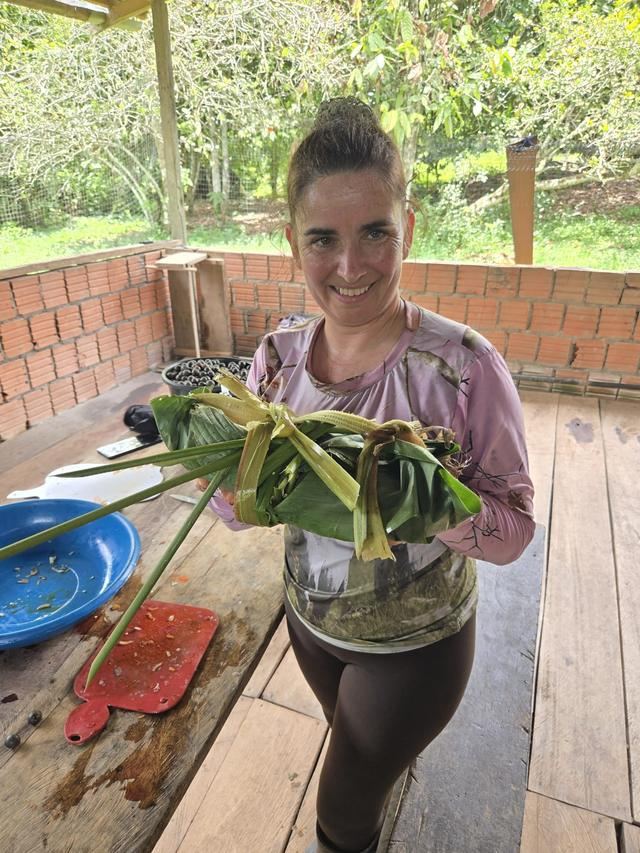 Une voyageuse présente un plat enveloppé dans des feuilles, préparé avec les cuisinières