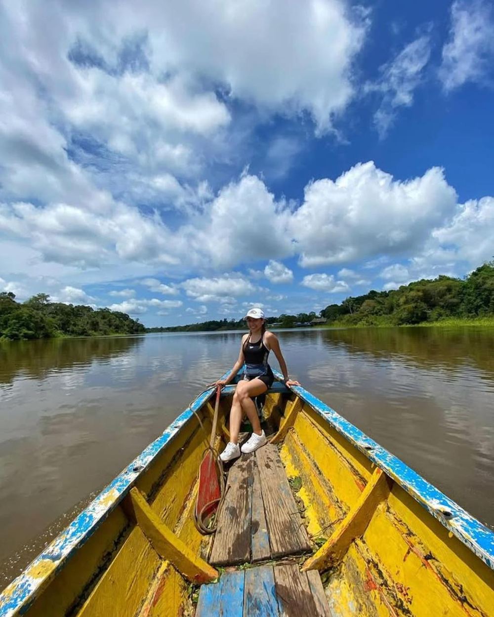 Una viajera sentada en la proa de un bote pintado, sobre el río